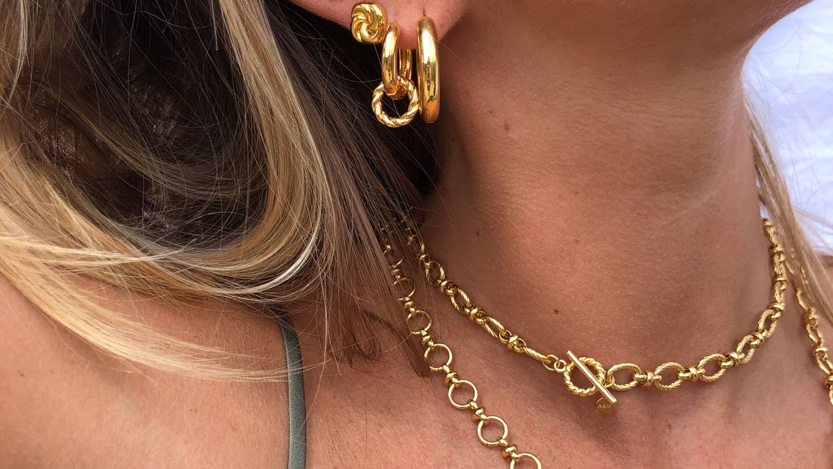 Woman wearing vintage inspired jewellery, including chunky hoops and chain necklaces