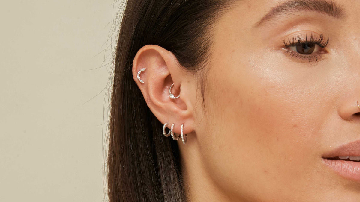 Woman wearing five solid gold small hoop earrings from Astrid & Miyu on her right ear.