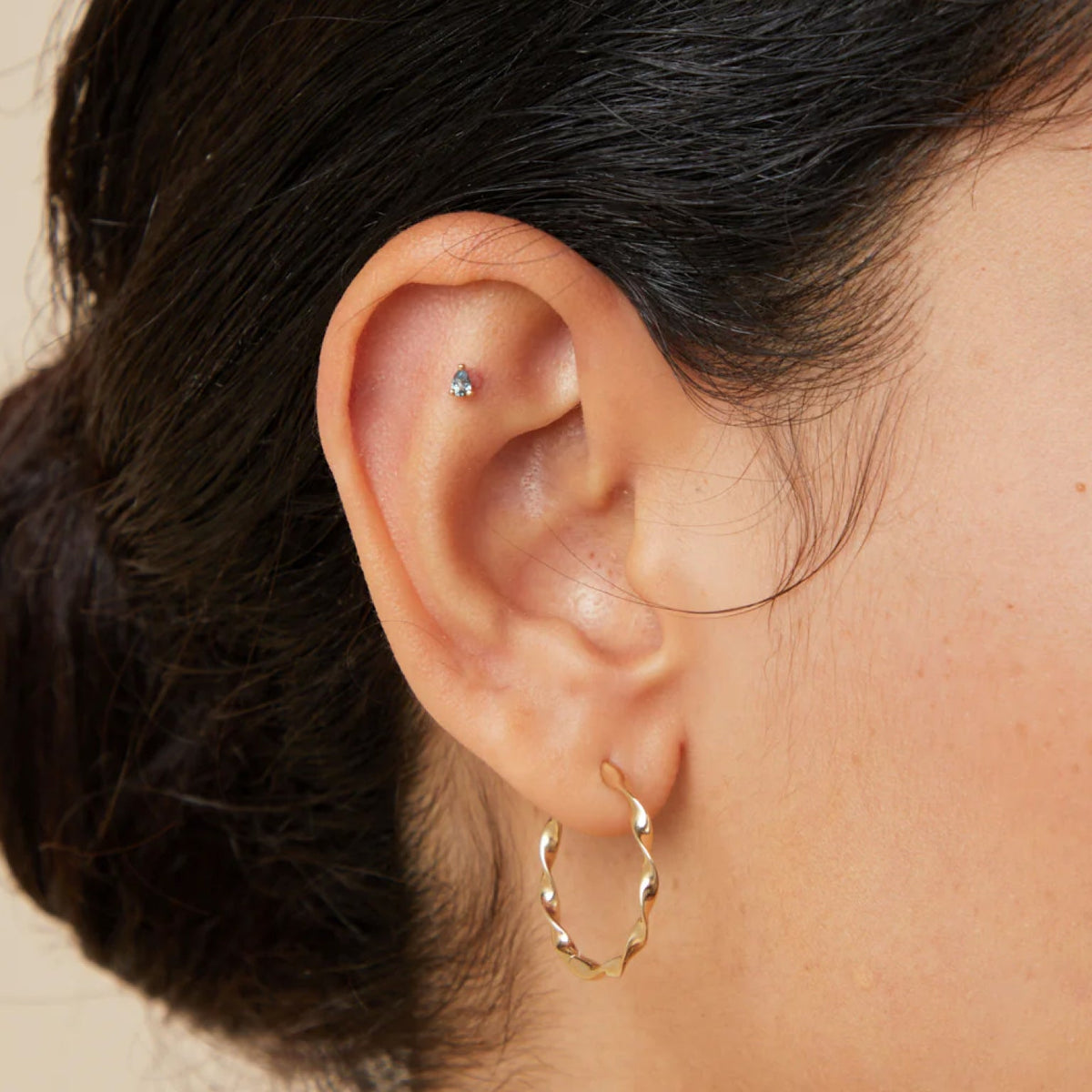 Woman wearing 2 pieces of solid gold cartilage earrings made with 14ct recycled gold from Astrid & Miyu.