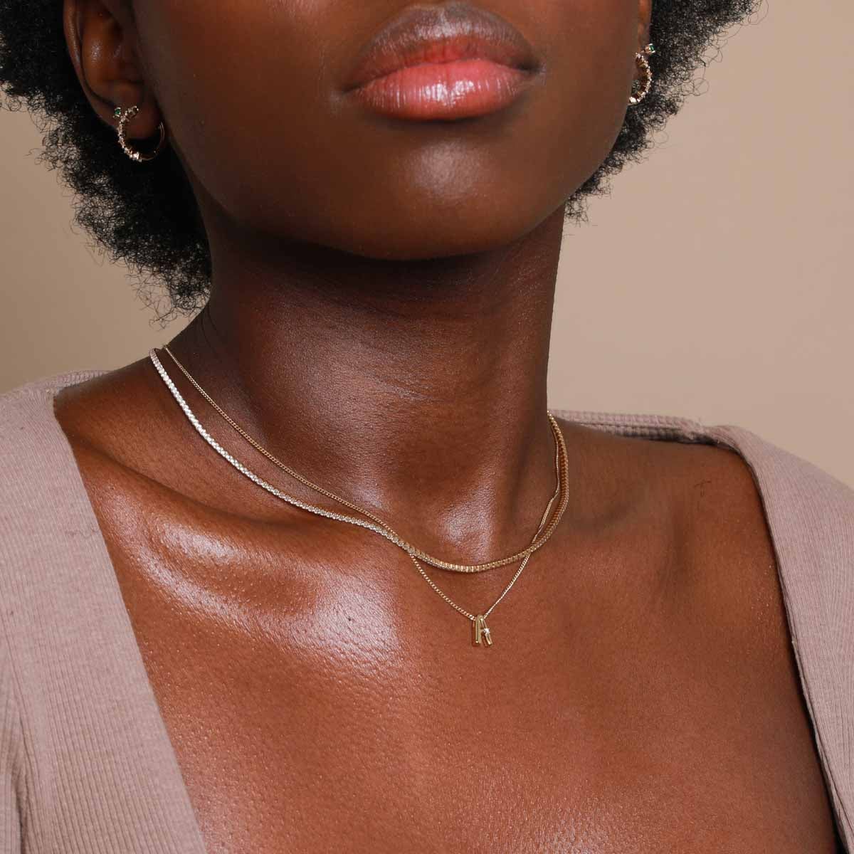 A Initial Pendant Necklace in Gold worn layered with snake chain necklace