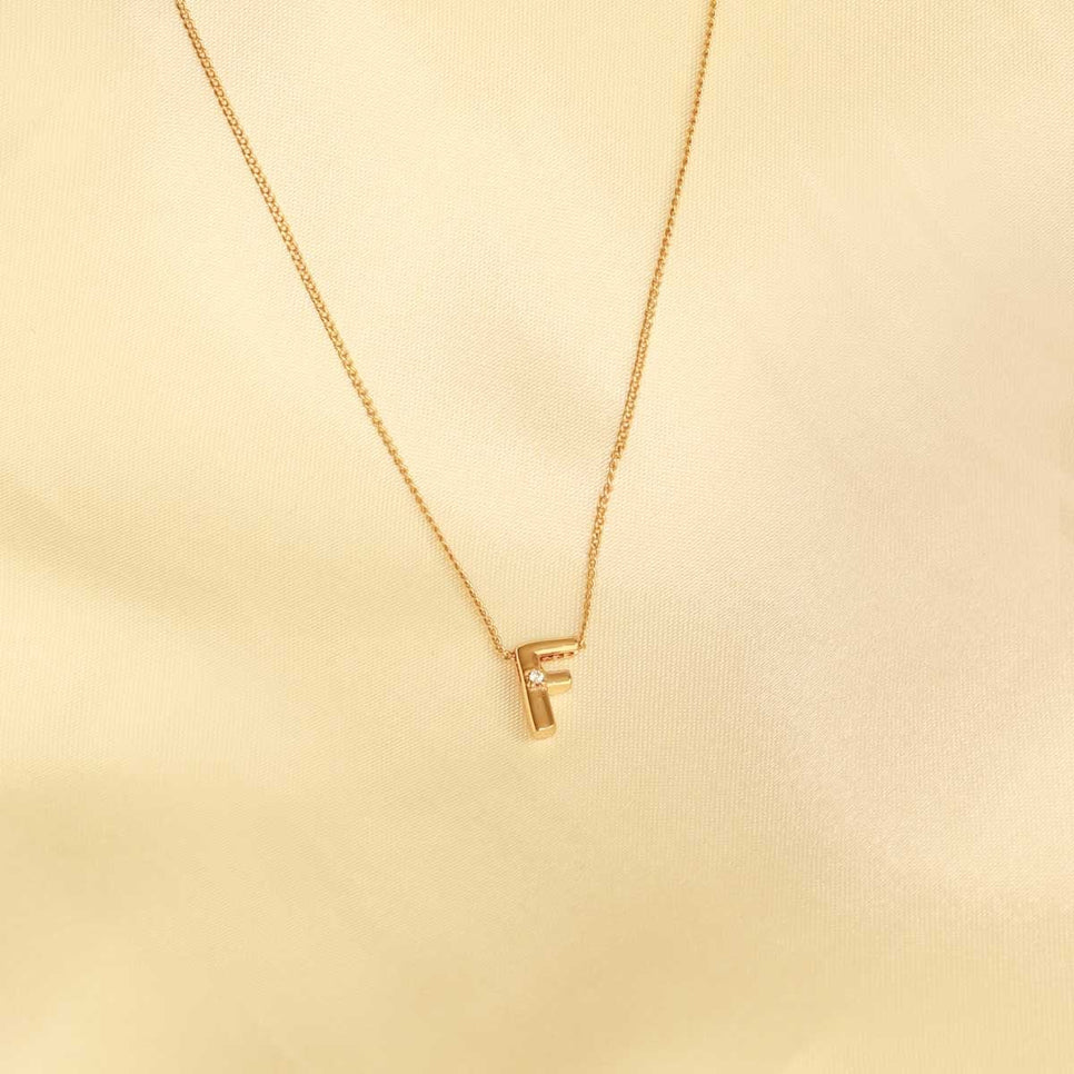 Flat lay shot of F Initial Pendant Necklace in Gold