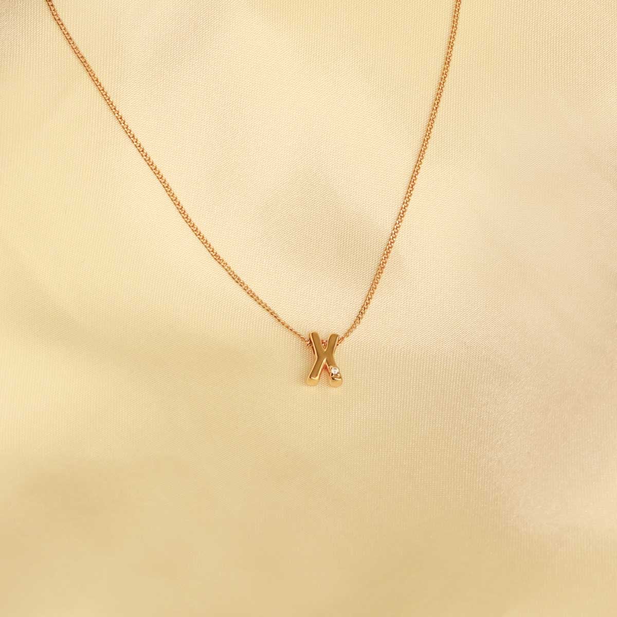 Flat lay shot of X Initial Pendant Necklace in Gold
