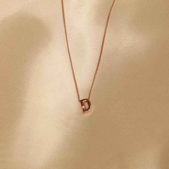 Flat lay shot of D Initial Pendant Necklace in Rose Gold