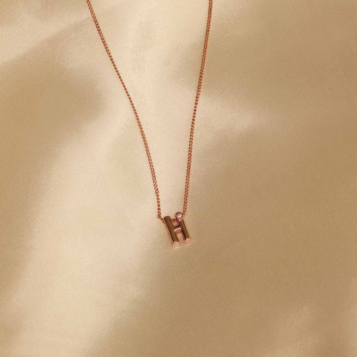 Flat lay shot of H Initial Pendant Necklace in Rose Gold