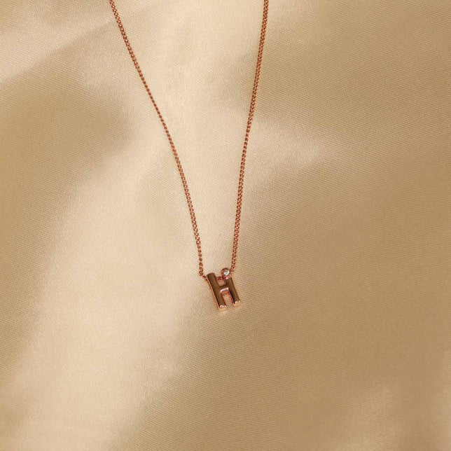 Flat lay shot of H Initial Pendant Necklace in Rose Gold