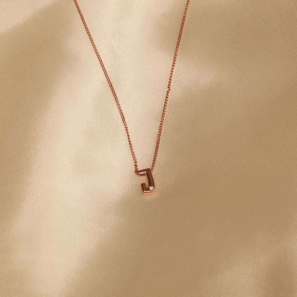Flat lay shot of J Initial Pendant Necklace in Rose Gold