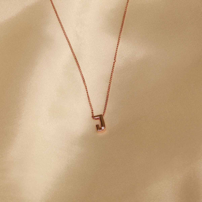Flat lay shot of J Initial Pendant Necklace in Rose Gold