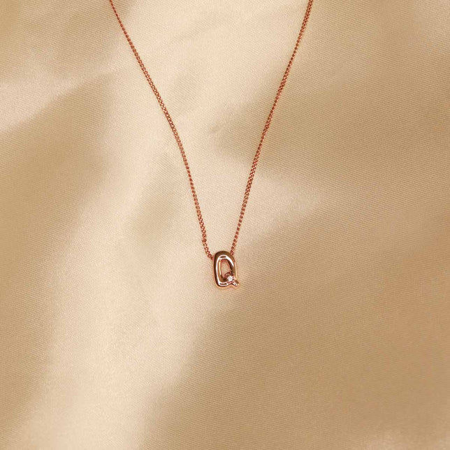 Flat lay shot of Q Initial Pendant Necklace in Rose Gold