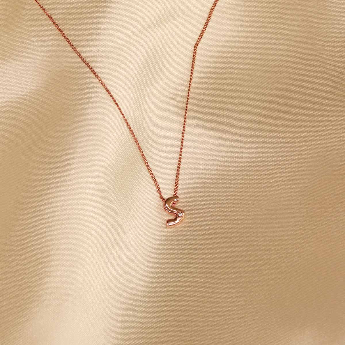 Flat lay shot of S Initial Pendant Necklace in Rose Gold