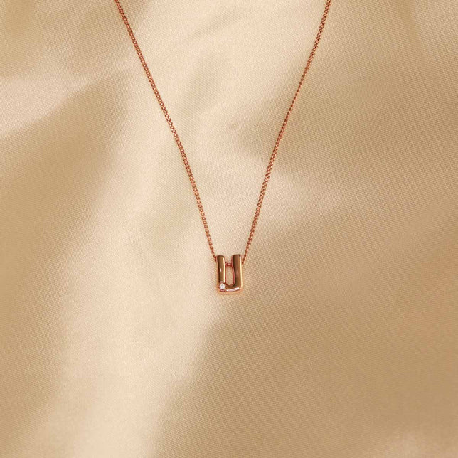 Flat lay shot of U Initial Pendant Necklace in Rose Gold