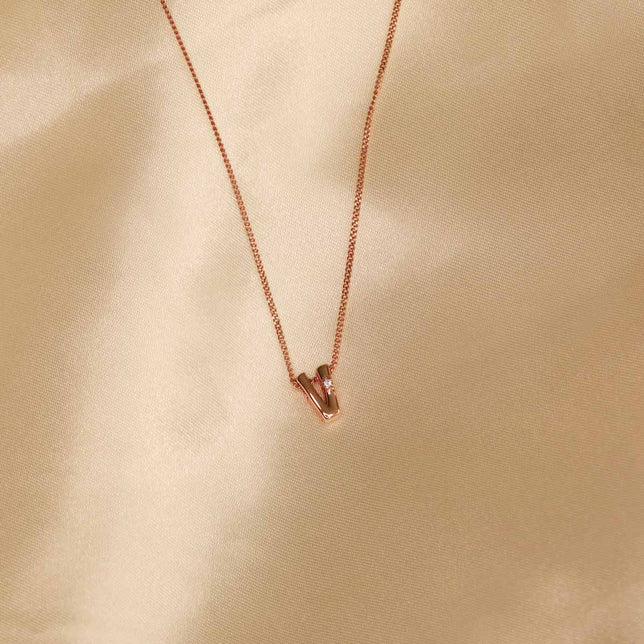 Flat lay shot of V Initial Pendant Necklace in Rose Gold