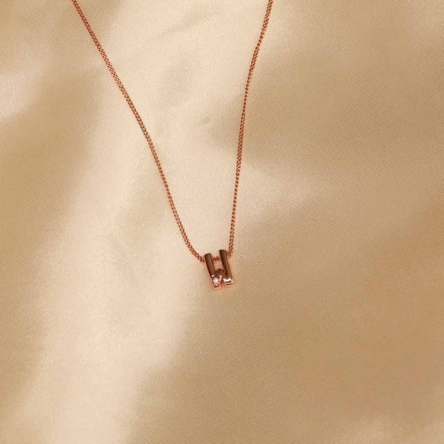 Flat lay shot of W Initial Pendant Necklace in Rose Gold