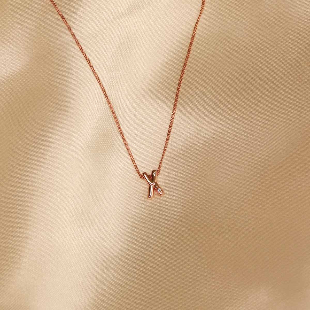 Flat lay shot of X Initial Pendant Necklace in Rose Gold