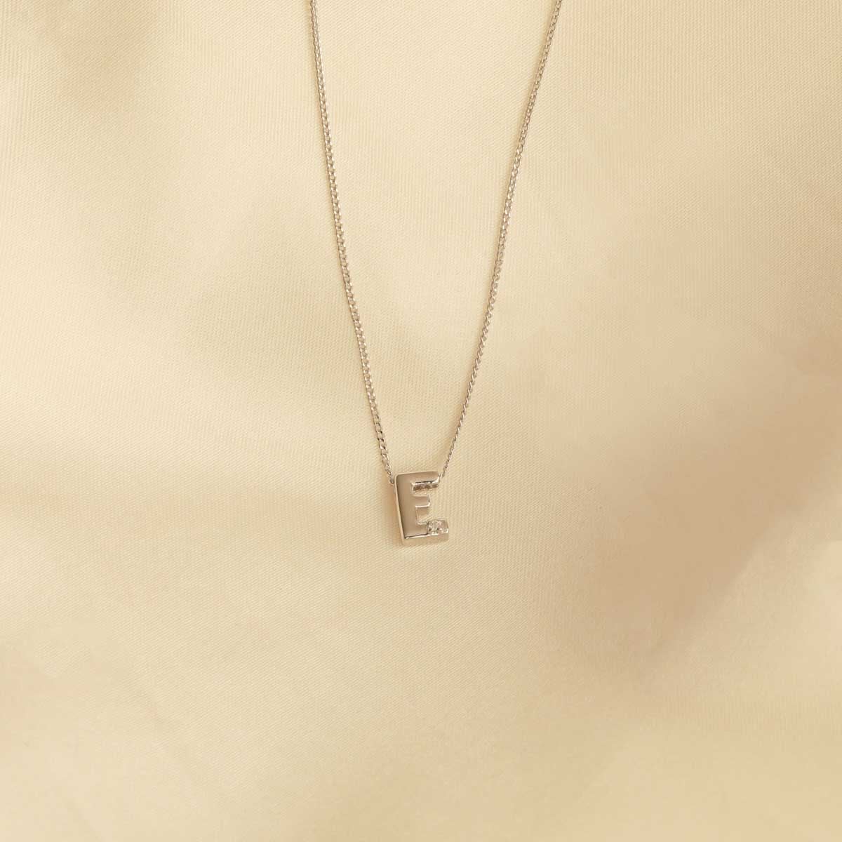 Flat lay shot of E Initial Pendant Necklace in Silver