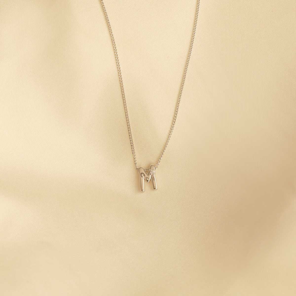 Flat lay shot of M Initial Pendant Necklace in Silver