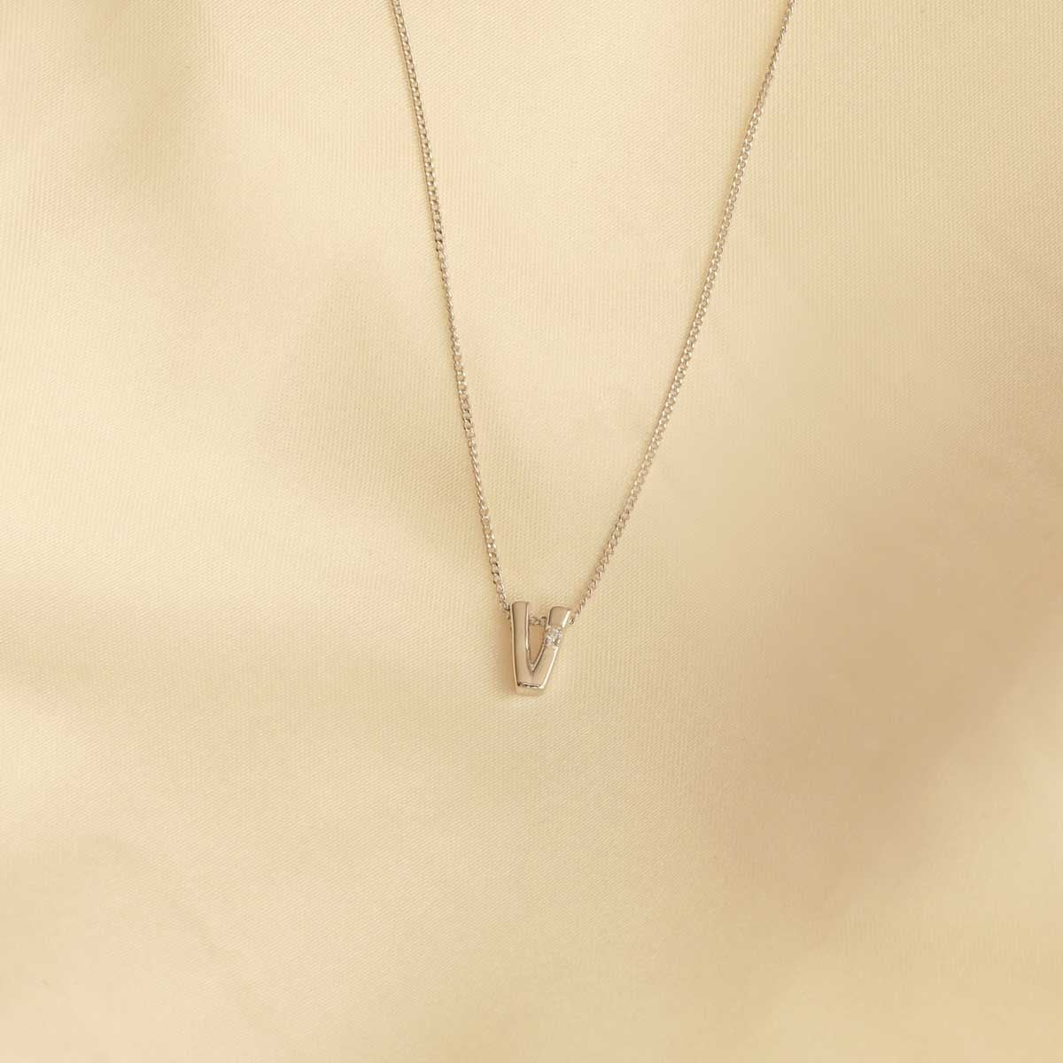 Flat lay shot of V Initial Pendant Necklace in Silver
