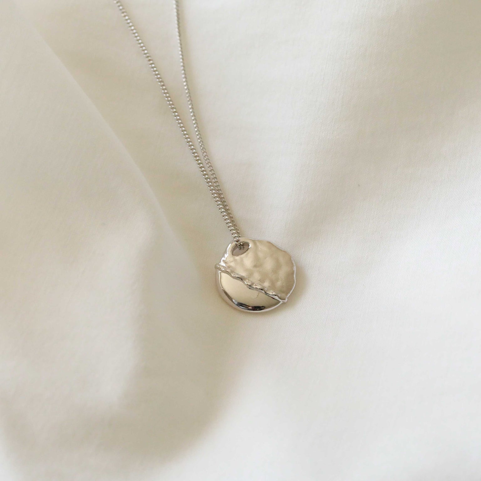 Flat lay shot of Molten Coin Pendant Necklace in Silver