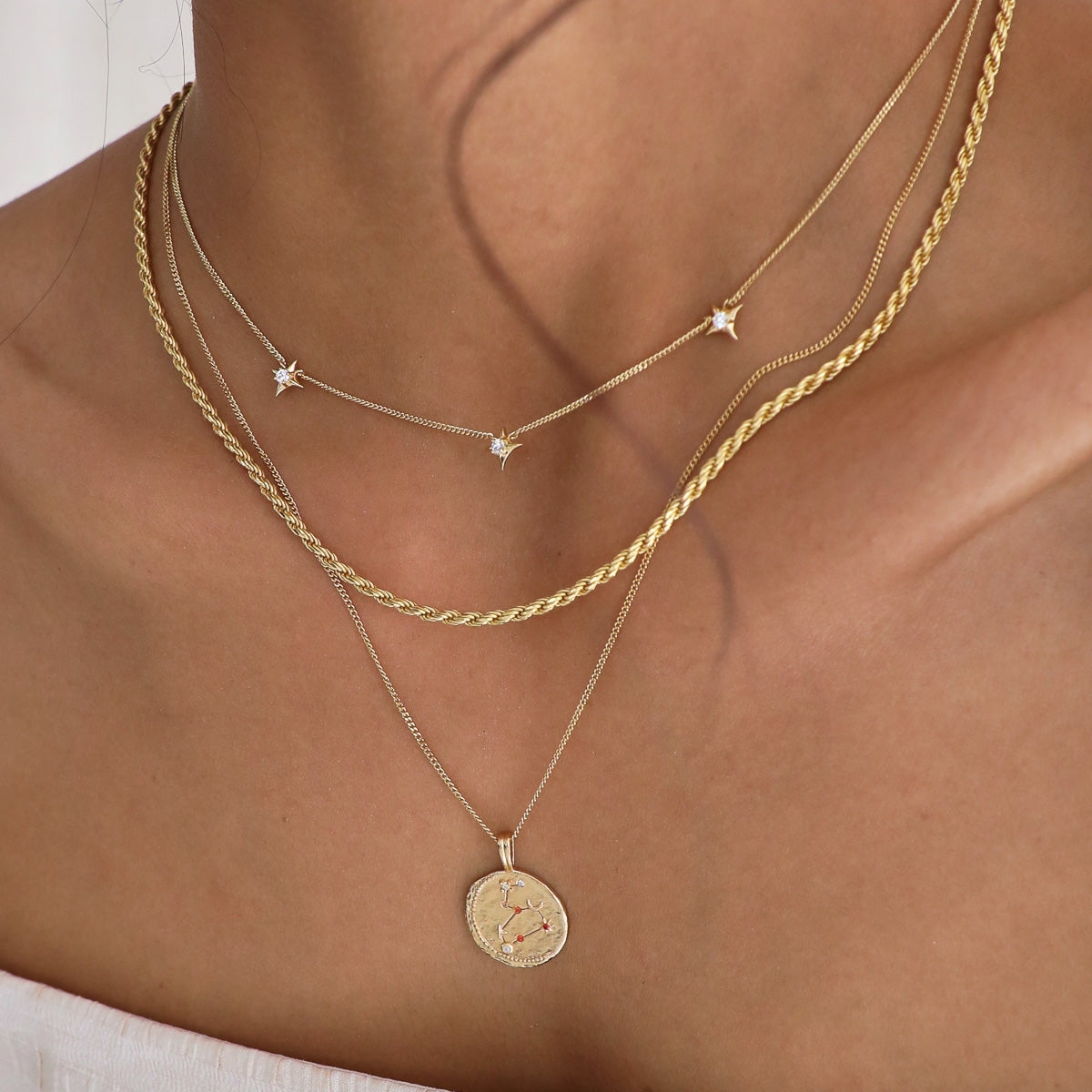 Cosmic Star Charm Necklace in Gold stacked with rope chain necklace in gold and a zodiac pendant necklace