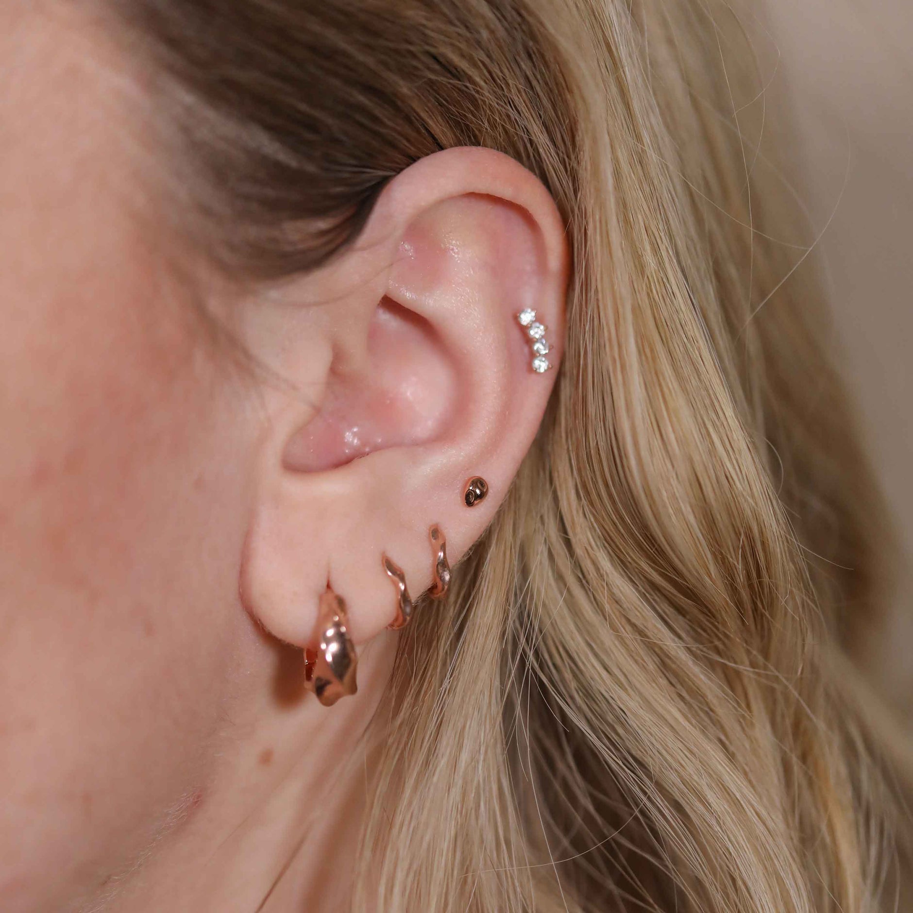Molten Stud Earrings in Rose Gold worn with curved crystal barbell and elemental huggies