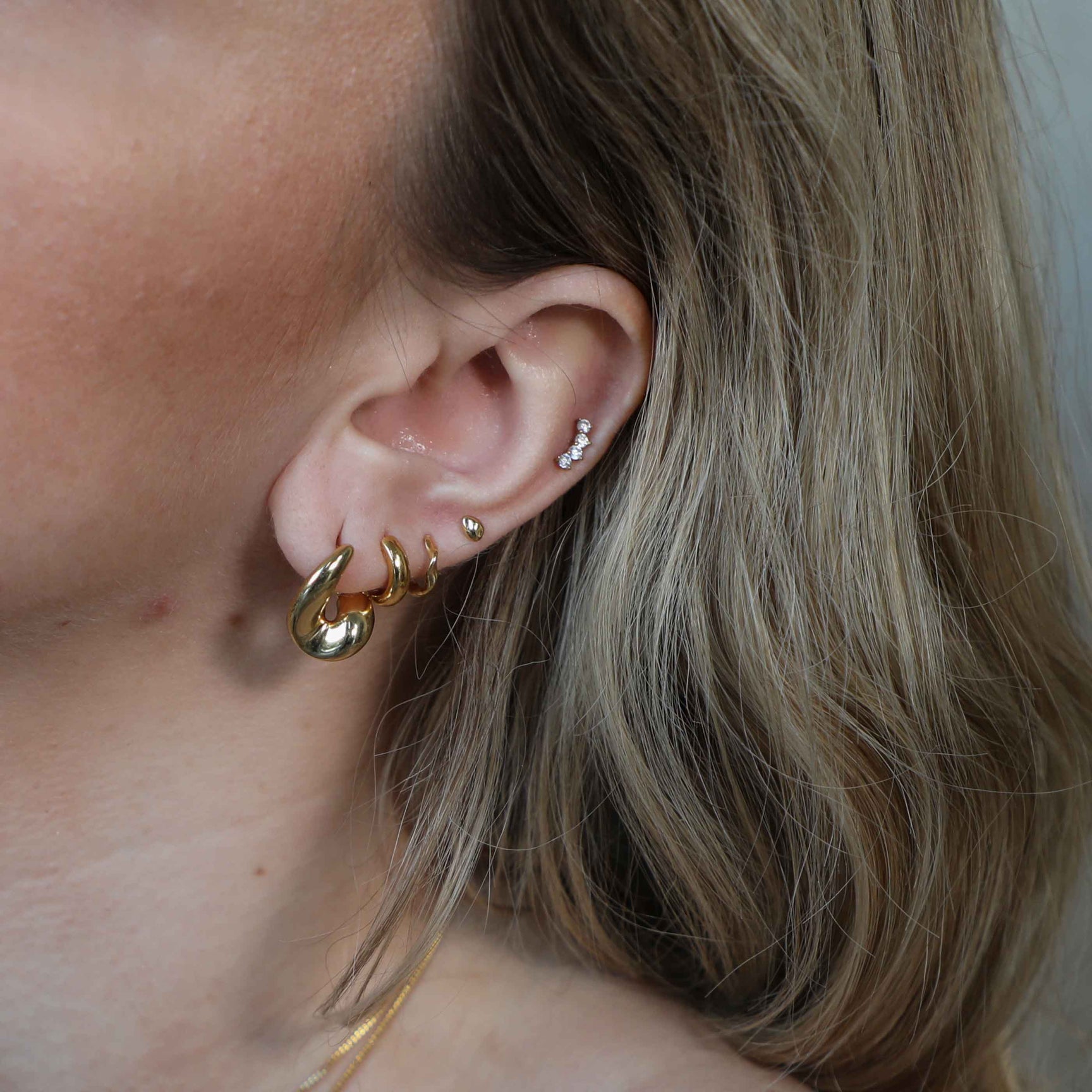 Molten Stud Earrings in Gold worn with molten hoops and gold huggies