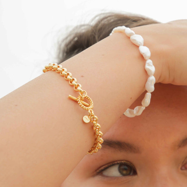 Worn shot of Wreath T-Bar Chunky Bracelet in Gold with pearl bracelet